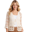 A woman wears the Pine Apparel Tie Front Crochet Cardigan in cream over a white top and tan pants, smiling at the camera against a white background.