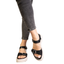 A person stands against a white background wearing CORKY'S FOOTWEAR INC That's Just Me Platform Sandal in Black with adjustable silver buckles and light soles, paired with dark grey rolled-up jeans.