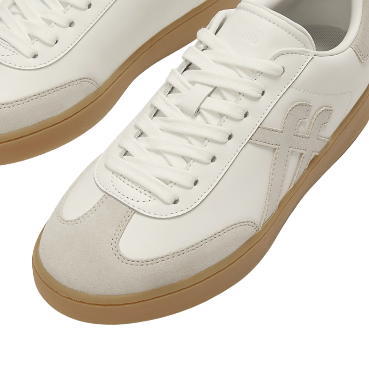 The Dash T-Toe Leather/Suede Sneaker by FITFLOP USA LLC features white leather, beige suede accents, gum soles, and a stitched side logo, shown from an overhead view.