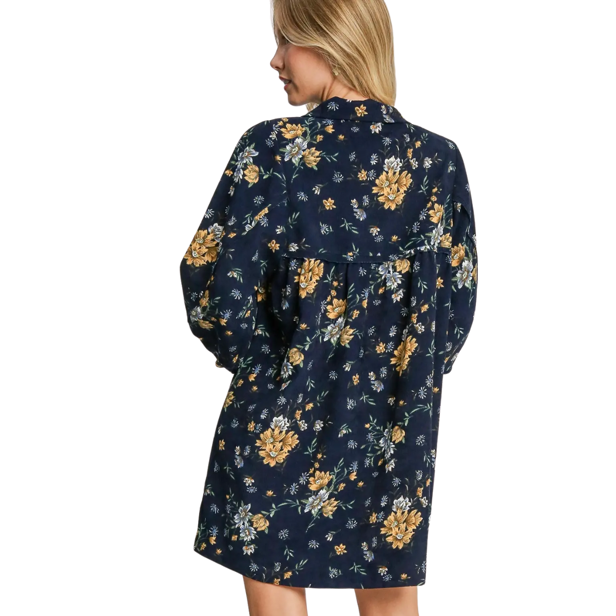 A blonde woman is seen from the back wearing the Umgee Floral Print Corduroy Short Dress, featuring long puff sleeves and a navy A-line silhouette with yellow and white floral patterns.