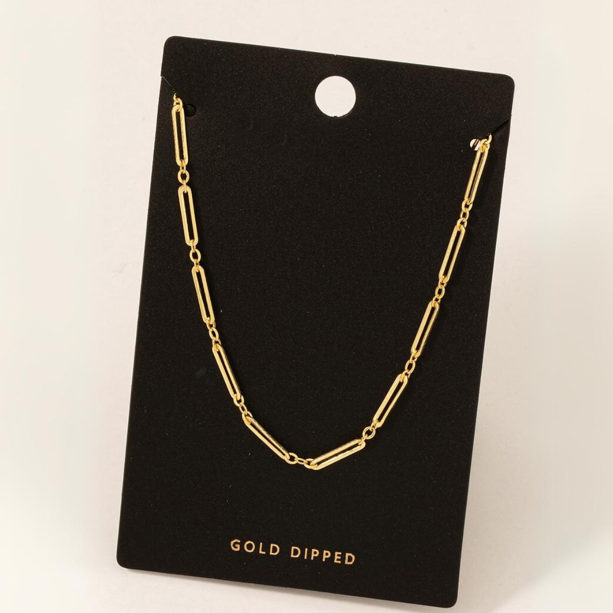 A Gold Dipped Dainty Oval Chain Necklace in Gold displayed on a black card with a hole at the top. The card proudly features "FASHION GO" written at the bottom.