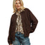 A woman models the Umgee Suede Look Ruched Zip Up Jacket over a floral blouse, paired with blue jeans, against a white background.