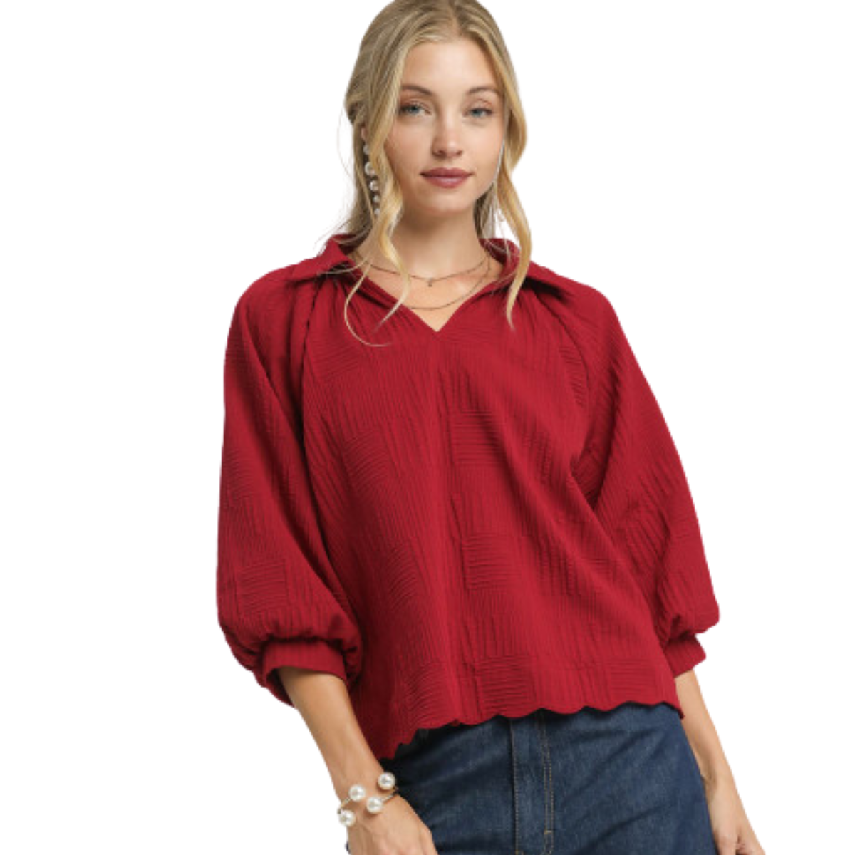 A woman wears the Umgee Crimson V-Neck Collared Blouse with batwing sleeves and dark blue jeans, standing against a white background.
