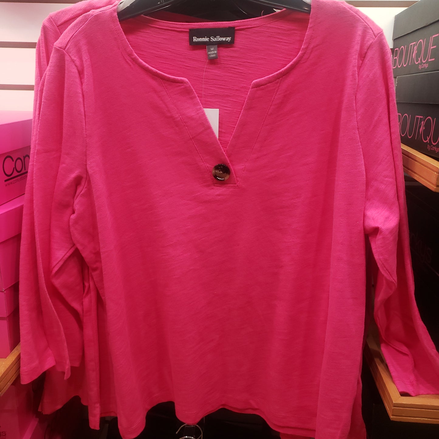 A 3/4 Cotton Top with Button Accent in Hot Pink by RONNIE SALLOWAY & CO INC is displayed on a hanger.