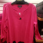 A 3/4 Cotton Top with Button Accent in Hot Pink with a V-neckline, wood button detail, and a label reading "RONNIE SALLOWAY & CO INC" hangs on a black hanger in a clothing store.