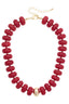 The San Sebastián Beaded Resin Necklace by Canvas Style features large round red resin beads, a central gold bead, and an adjustable gold chain clasp.