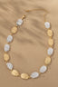 Two Tone Irregular Shape Hammered Beaded Necklace from FASHION GO arranged in a semi-circle with a solar ray pattern on a sandy background.