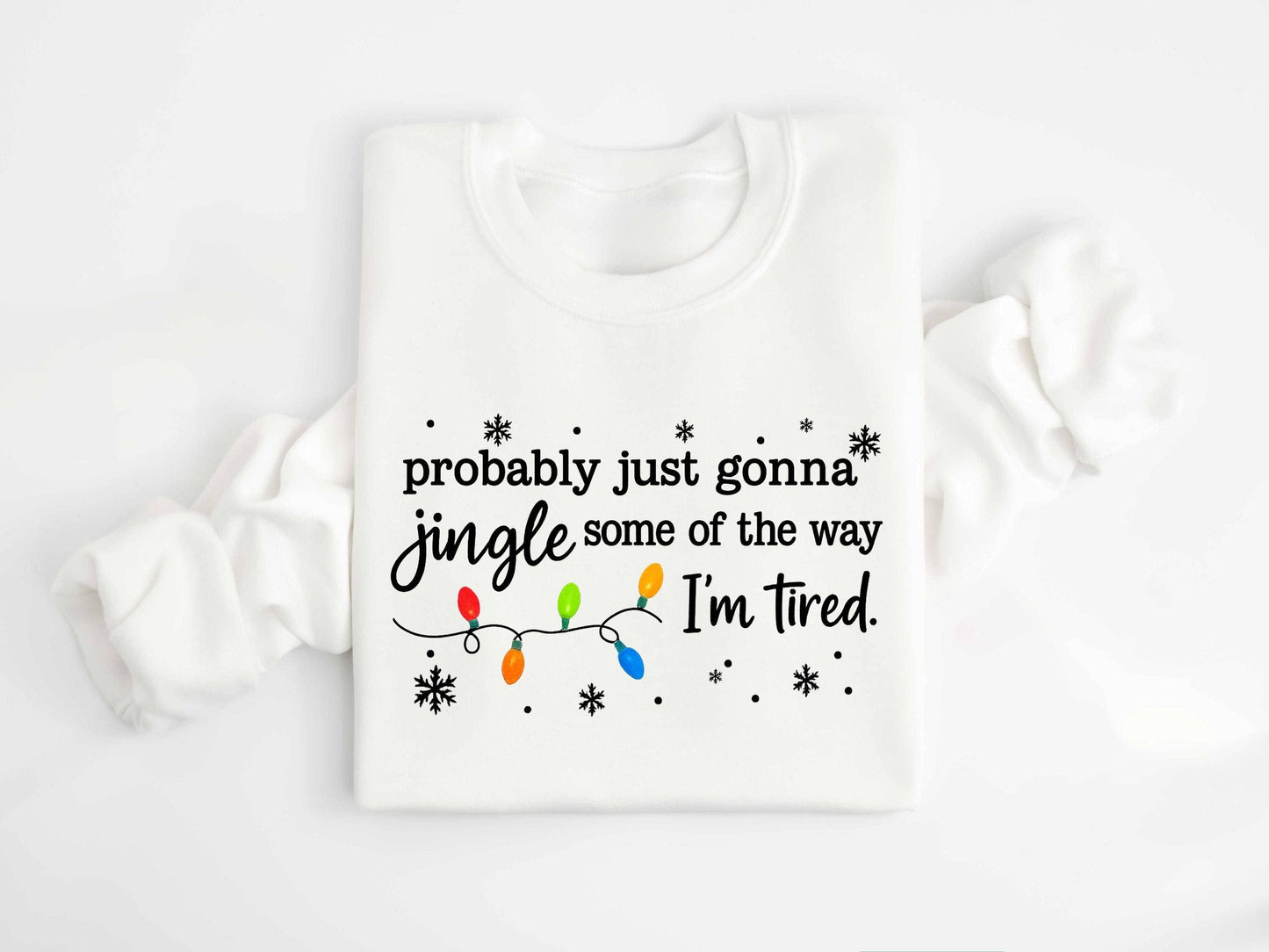 TheKingShirt’s Jingle All the Way Christmas Long Sleeve Shirt features festive Christmas lights and snowflakes, plus the humorous line: "probably just gonna jingle some of the way I'm tired," on a super soft sweatshirt.