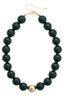 The Marjorie Game Day Beaded Necklace by Canvas Style features oversized, glossy black beads with a bold central gold bead, finished with a gold clasp and adjustable chain—making it the perfect statement necklace for any occasion.