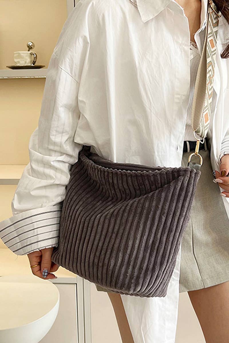 A person carries the 42POPS Corduroy Tote Bag With Guitar Shoulder Strap, paired with a white oversized shirt and gray skirt.