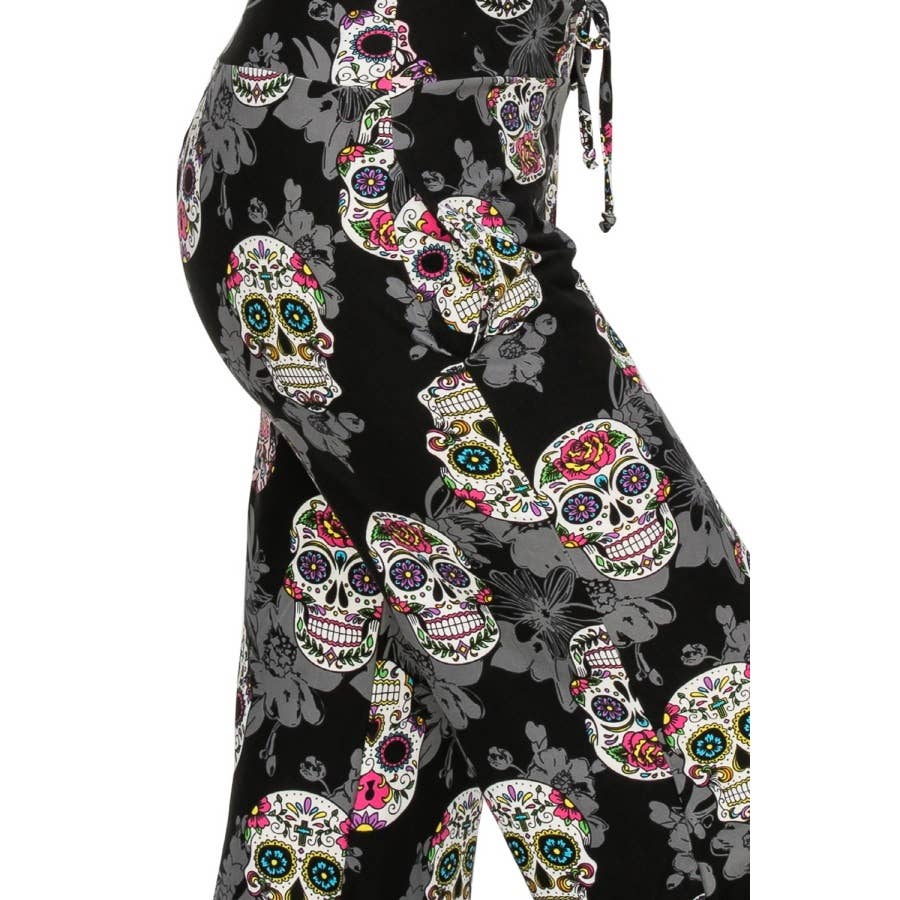 Close-up of a person wearing Leggings Depot Buttery Soft Print Pajama Pants with colorful sugar skulls, floral designs, and an elastic waistband.