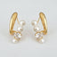 Experience timeless elegance with the Ellemadera Zircon Pearl Dangle Earrings. These earrings feature a graceful curved gold design, each adorned with three radiant white pearls and a sparkling clear zircon gemstone. Perfect for those who appreciate classic sophistication, the earrings are beautifully displayed against a simple white background.