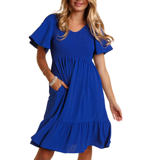 A woman wearing a blue, knee-length V-neck Fit and Flare Solid Dress with Side Pockets by FASHION GO, with short flutter sleeves, standing against a white background.