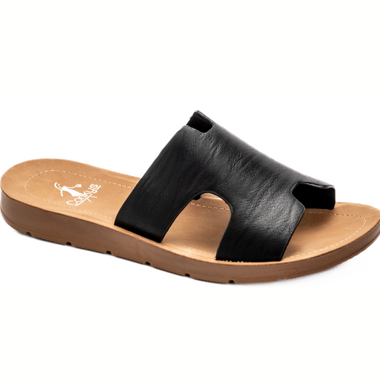 A timeless black leather Bogalusa Slide Sandal by Corkys with a single wide strap and flat brown sole, displayed on a white background.