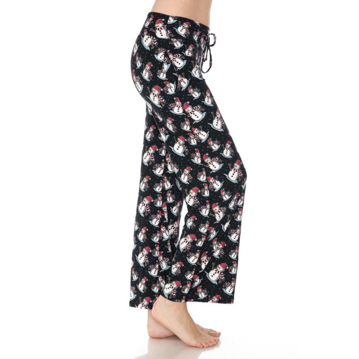 Standing barefoot on a white background, a person wears FASHION GO's buttery soft, black pajama pants adorned with a snowman pattern. These cozy pajama pants, officially named "Buttery Soft Pajama Pants with Drawstring," feature an elastic waistband for ultimate comfort and functional pockets for keeping essentials close by.