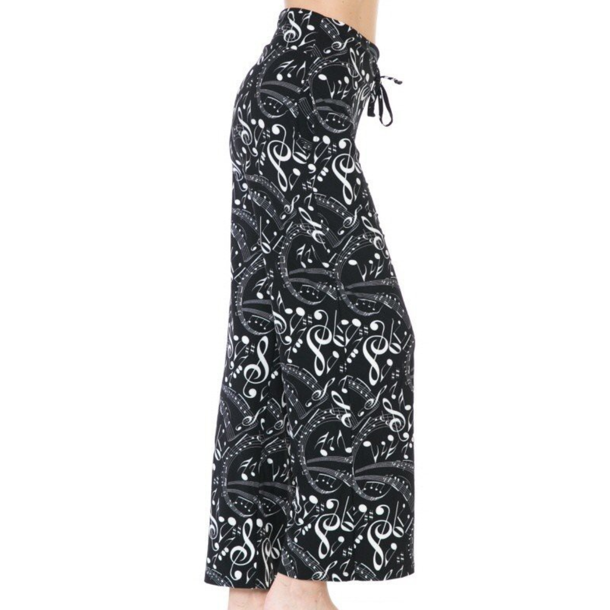 A person wearing the FASHION GO Buttery Soft Pajama Pants with a black and white music note pattern, featuring a drawstring waistband and functional pockets, photographed from the side.