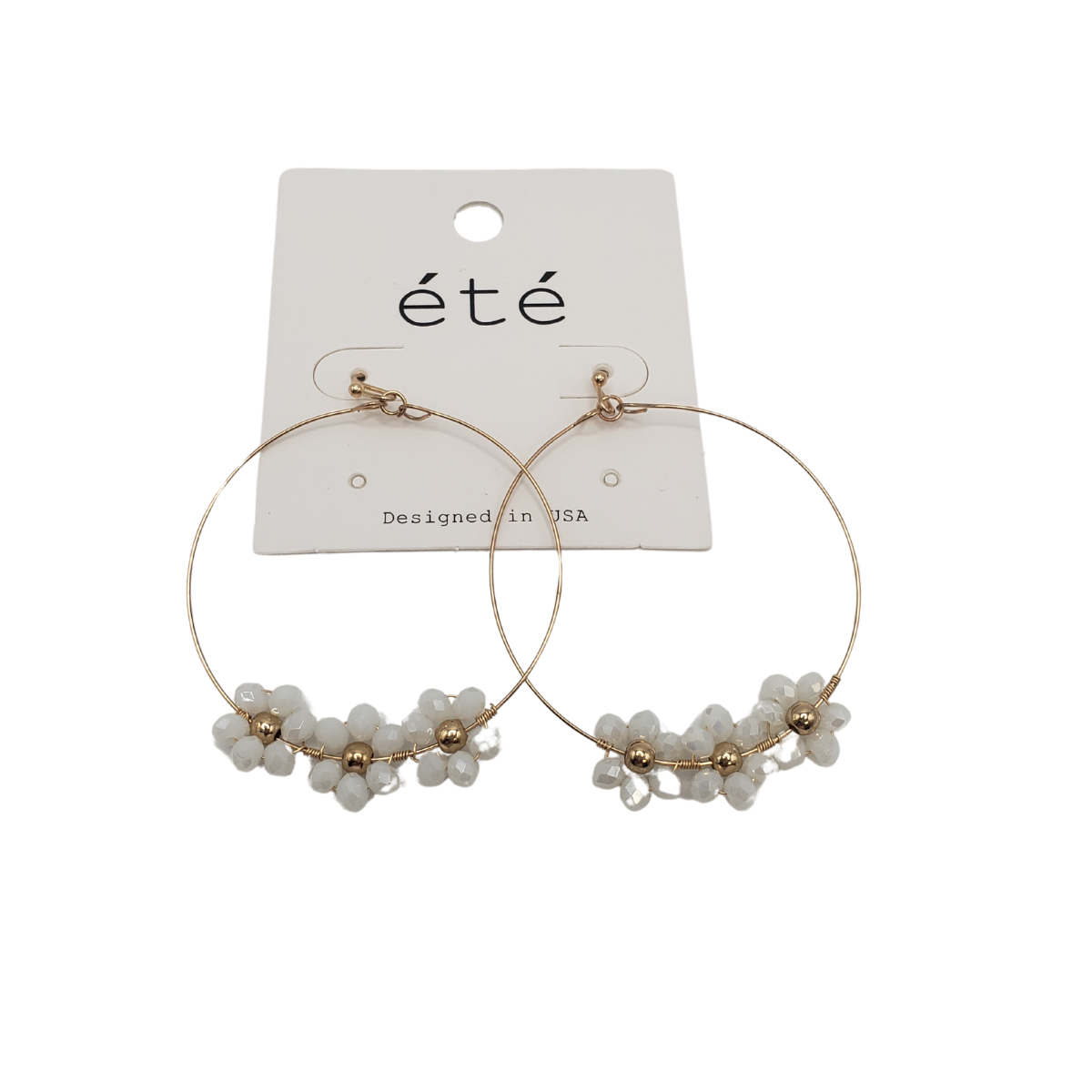 The Crystal Flower Hoop Earrings by SPECIAL EFFECTS showcase a timeless design with gold hoops, intricate white flowers, and sparkling crystals, elegantly presented on an "été" branded card.