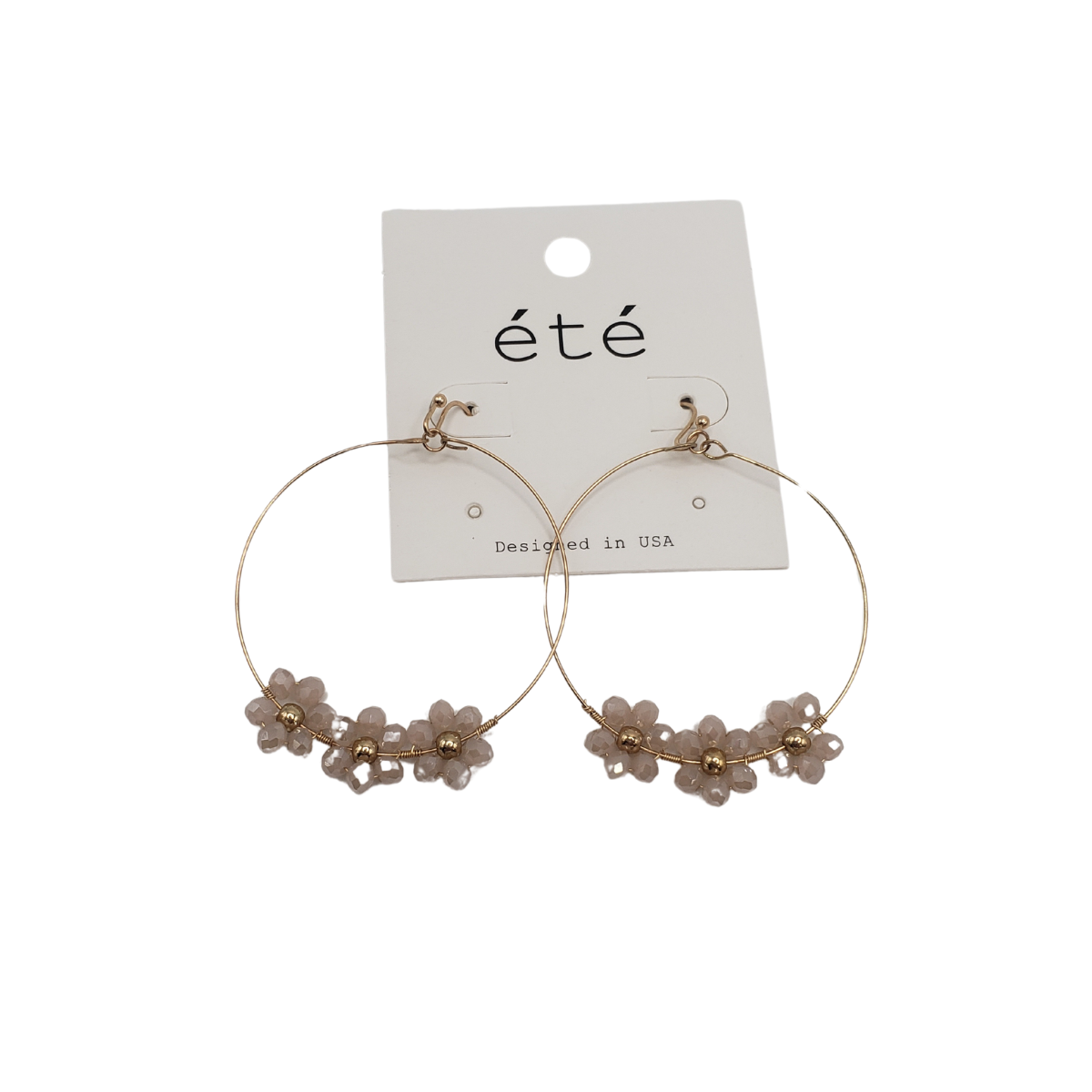 Crystal Flower Hoop Earrings by SPECIAL EFFECTS have a timeless design with gold hoops adorned with small pink flowers, displayed on a white card labeled "été.
