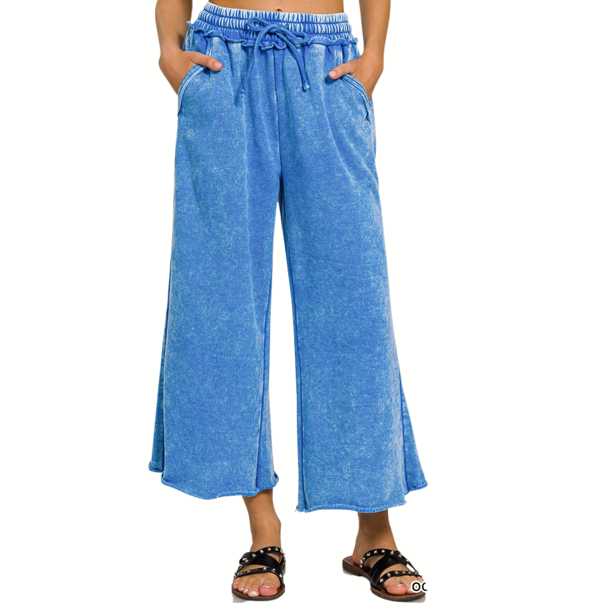 A person wears FASHION GO’s blue Acid Washed Fleece Palazzo Sweatpants with a drawstring waist and pockets, paired with black sandals, shown from the waist down against a white background.