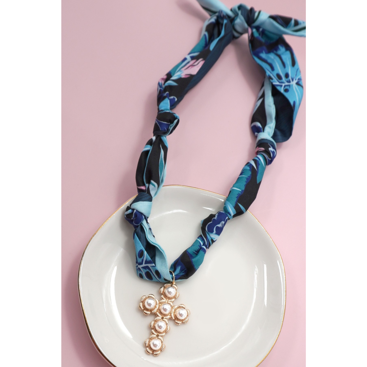 The FASHION GO Handmade Scarf Necklace in assorted colors and patterns is shown on a white plate with a light pink background.
