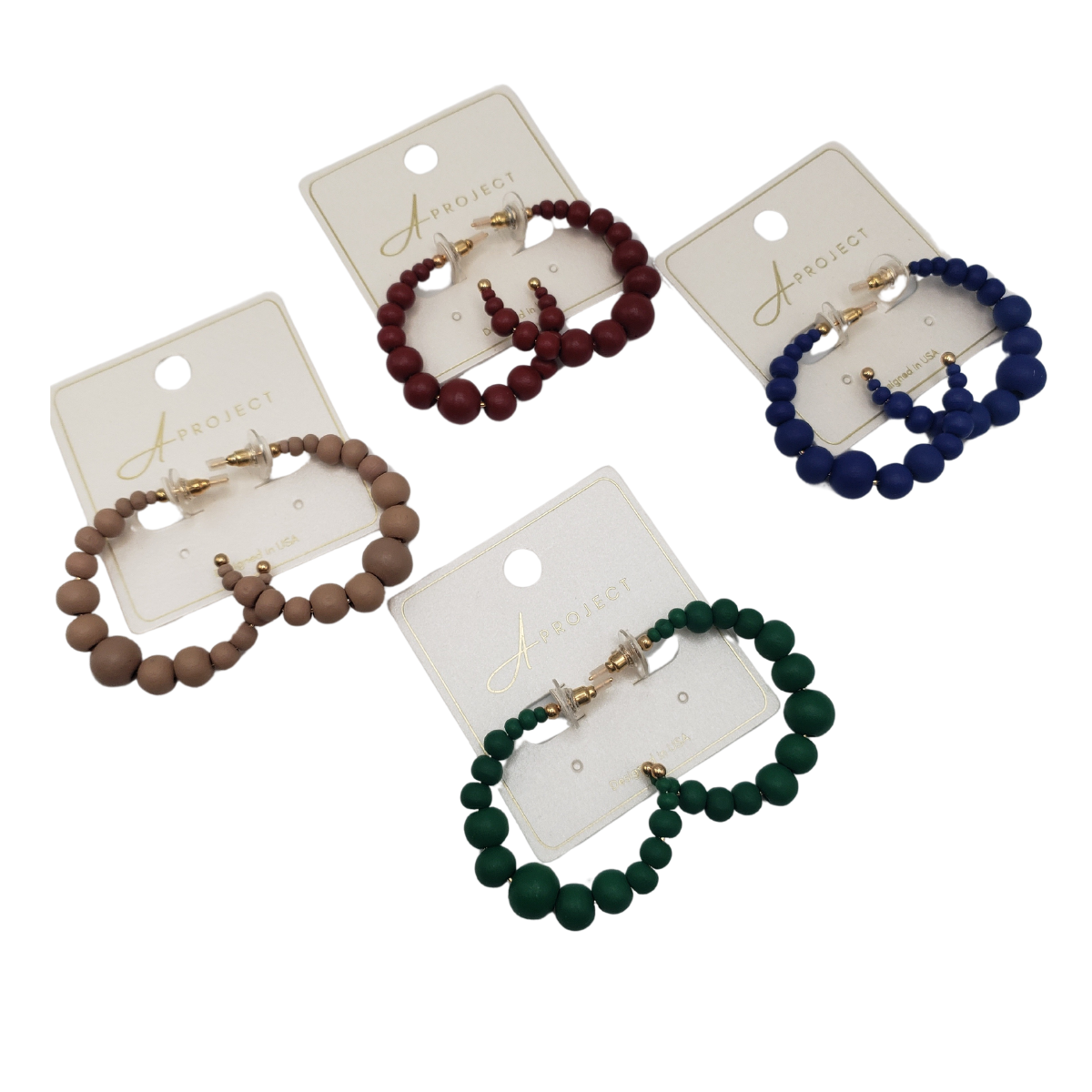 Four pairs of SPECIAL EFFECTS Color Balls Hoop Earrings in beige, maroon, blue, and green are elegantly displayed on cards labeled "Aproject.
