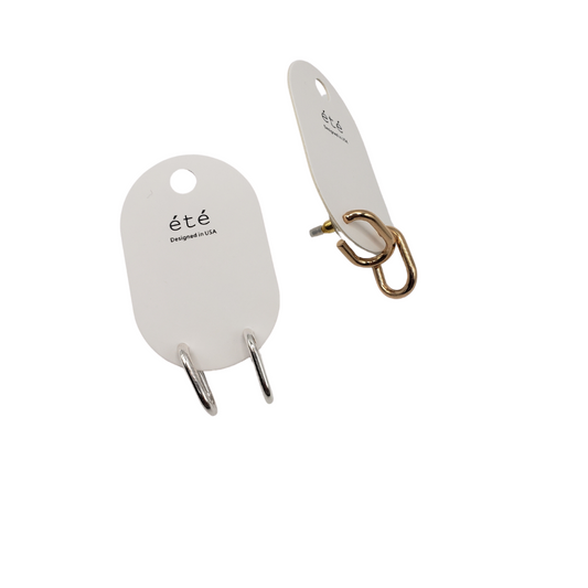 Two sets of earrings on white "été" cards by SPECIAL EFFECTS. One pair features a silver small hoop design, named J Hook Earring. The other showcases a gold tone with an intertwined double hoop motif.