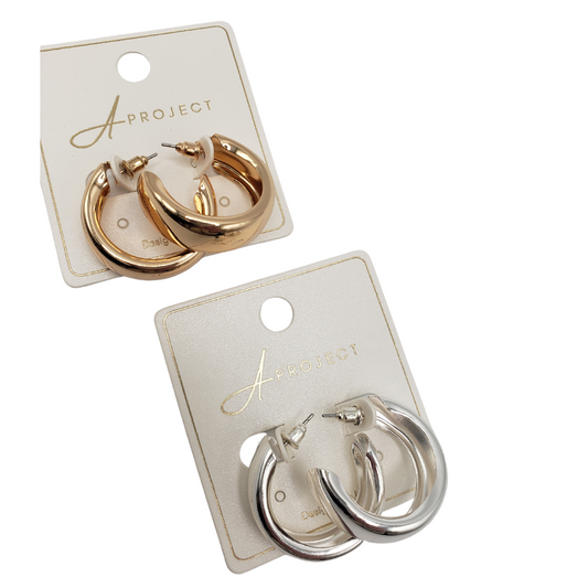 Two sets of SPECIAL EFFECTS Thick Tube 30mm Hoop Earrings, one gold-toned and one silver-toned, are elegantly presented on cards labeled "Project." These trendy hoops are perfect for any occasion.