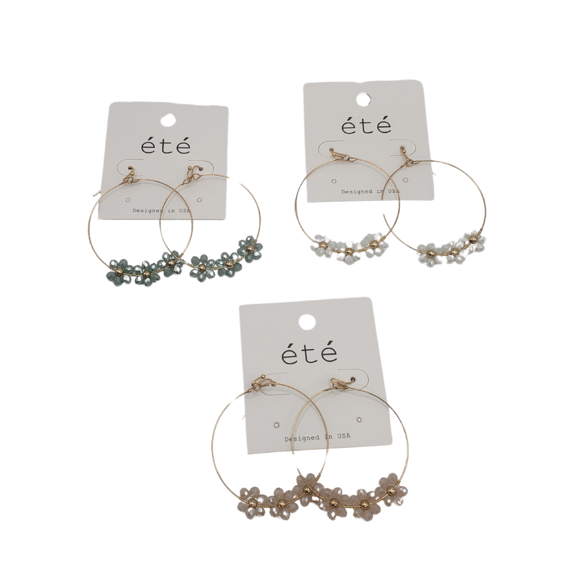 Three pairs of timeless Crystal Flower Hoop Earrings by SPECIAL EFFECTS are displayed on white cards labeled "été," featuring blue, white, and beige flowers beautifully complementing the sparkling crystals.