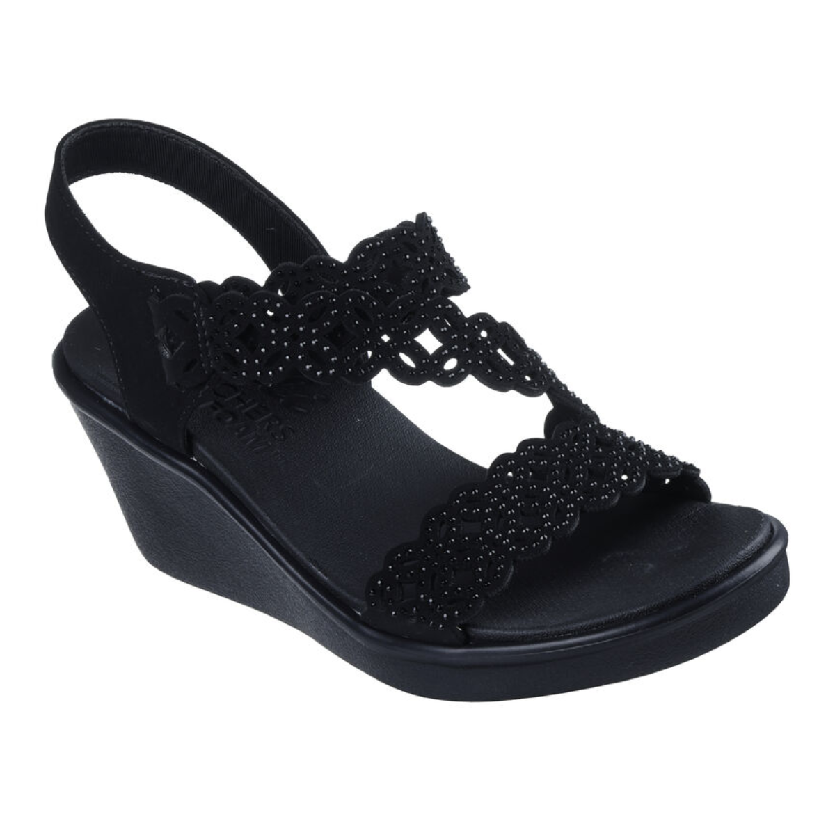The Sassier Dayz in Black by SKECHERS USA INC is a black wedge sandal featuring two scalloped straps with small decorative holes and a slingback design.