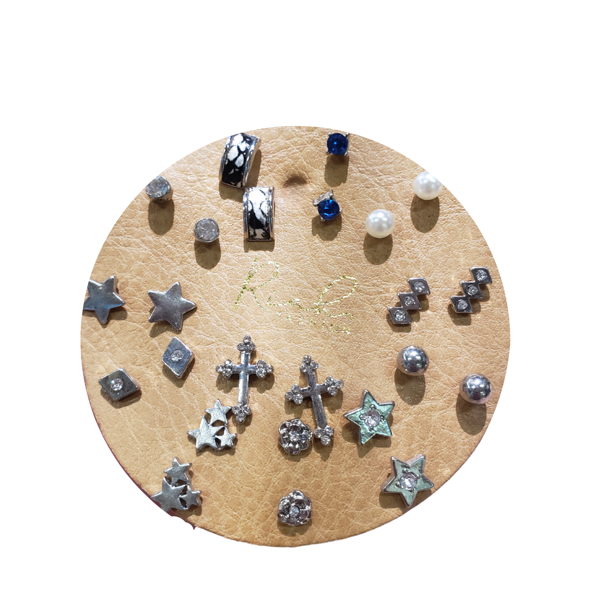 A circular leather display features a dozen pairs of MYE1351 STUDS by Fashion Go, showcasing small stud earrings in shapes like stars, crosses, and elegant pearls.