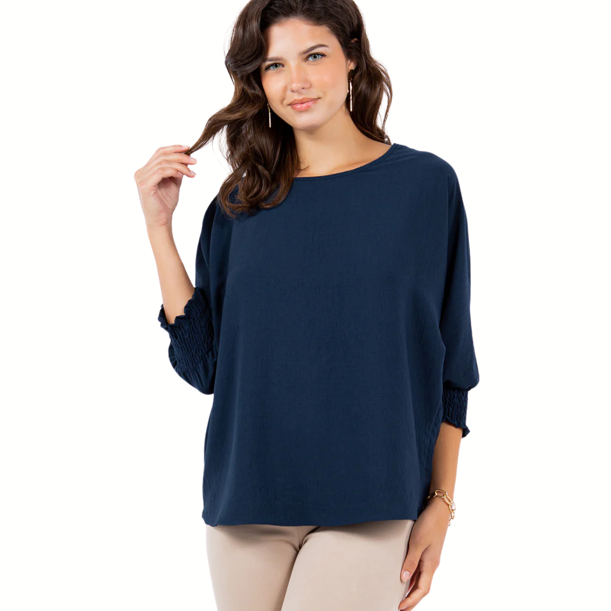 A woman wears the LTX Air Flow Top with smocking cuffs in navy blue and beige pants, standing against a white background.
