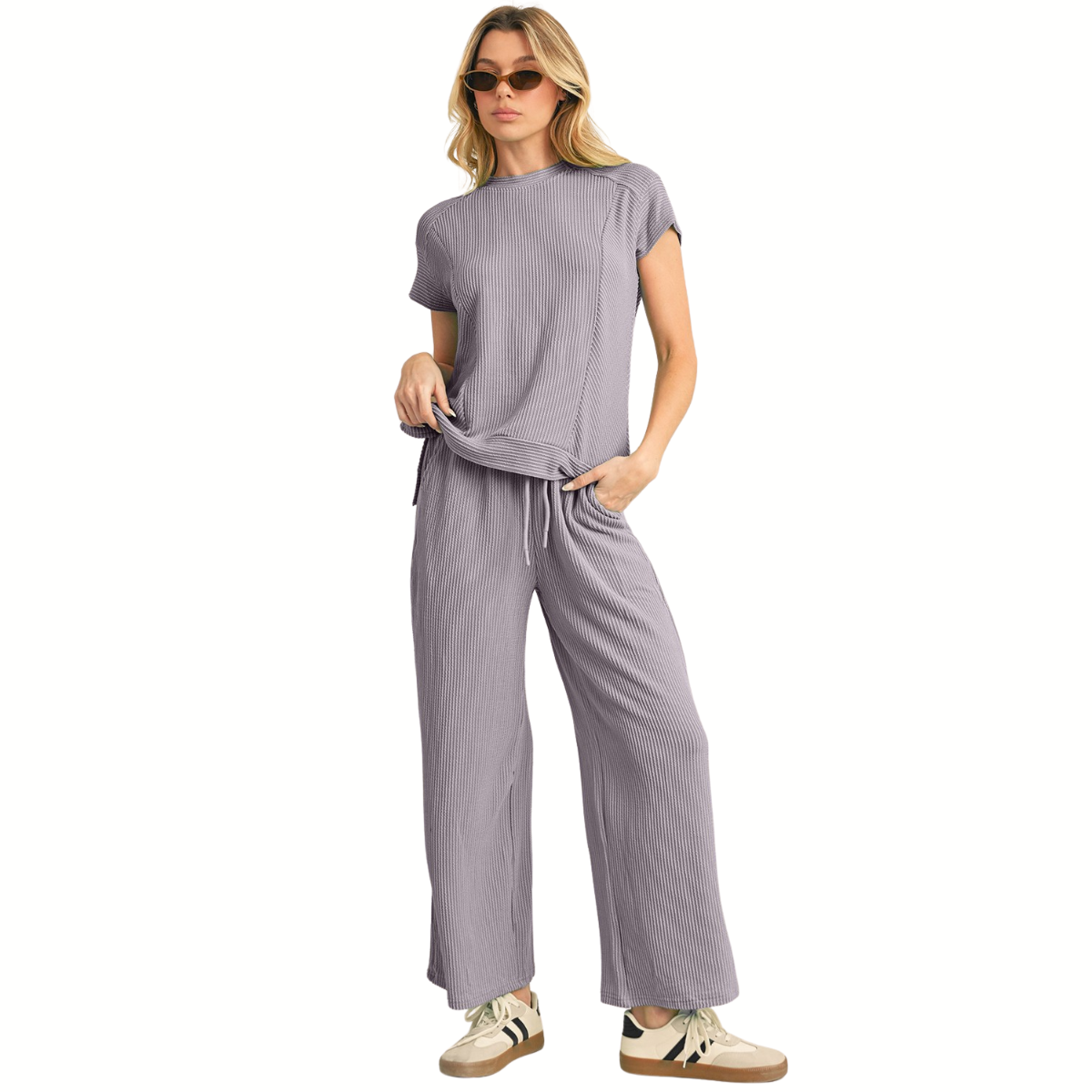 A woman wears the Shewin Corded Spring T Shirt And Wide Leg Pants Set in light purple, featuring short sleeves and wide leg pants, styled with sunglasses and beige sneakers for a versatile look.