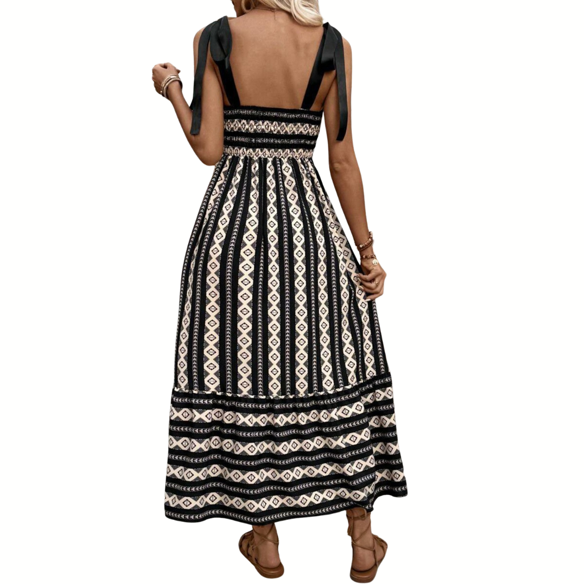 A woman stands with her back to the camera wearing Shewin's Ethnic Print Stripe Knot Strap Maxi Dress, a trendy sleeveless piece featuring black and cream geometric patterns in lightweight fabric.