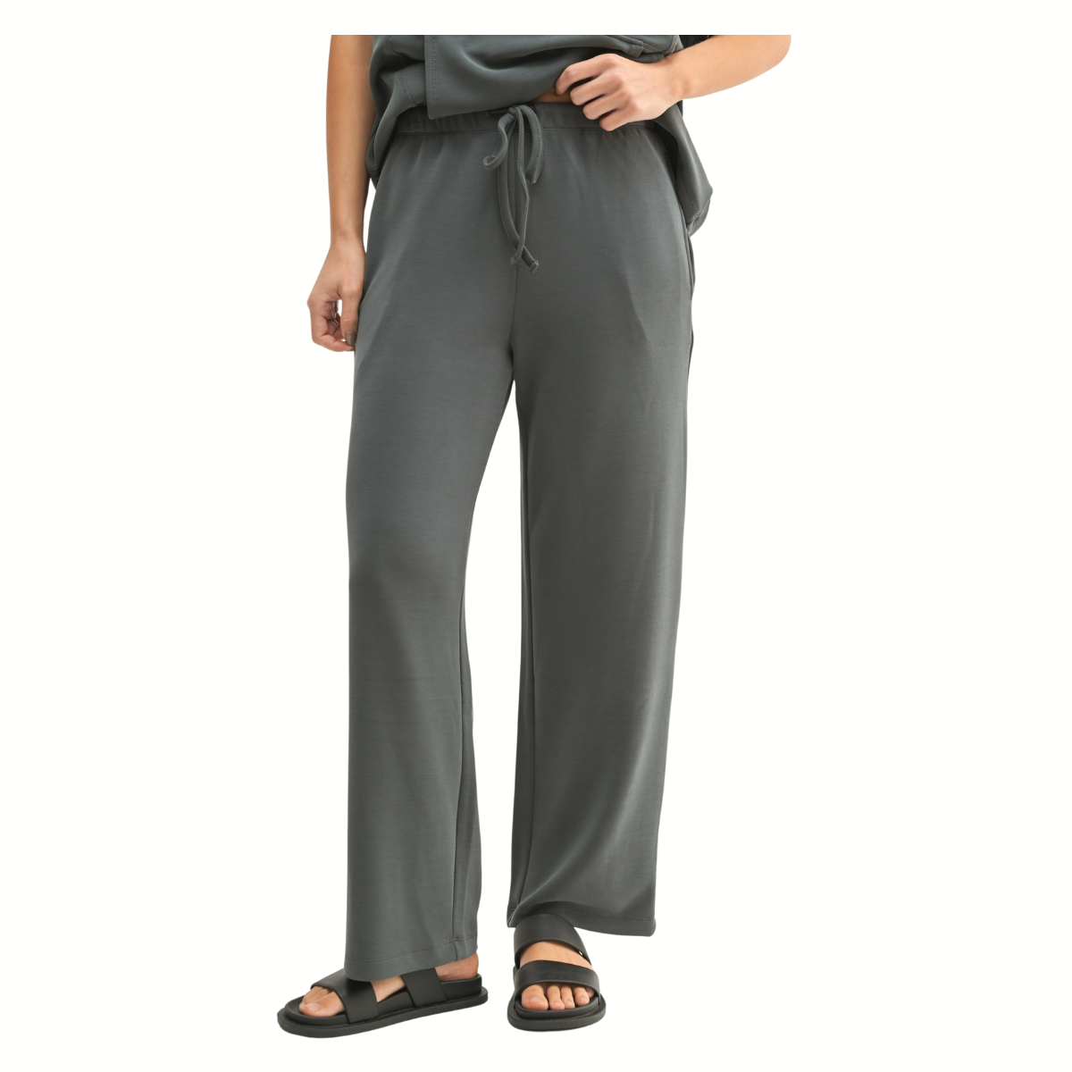 A person wearing the Mono B Laguna Cowl Neck Wide Leg Pant Set—loose gray wide-leg pants with a matching cowl neck top and black sandals—shown from shoulder down against a white background.