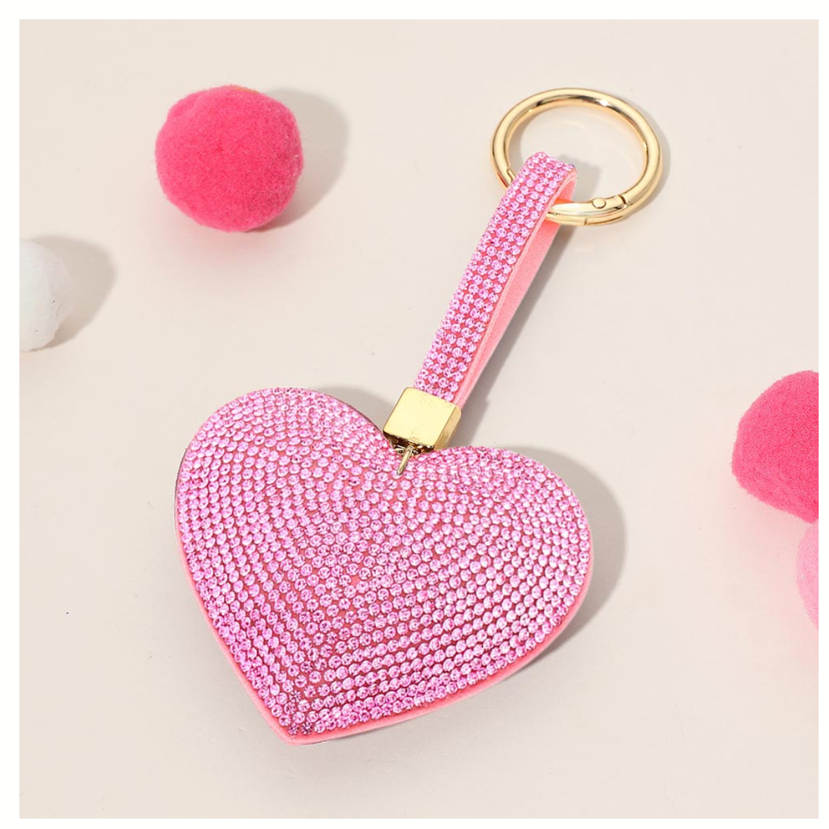The Wona Trading Bling Heart Key Chain Bag Charm in assorted colors features rhinestones and a gold ring, shown with pink and white pom-poms—a stylish accessory to add sparkle to your bag or keys.