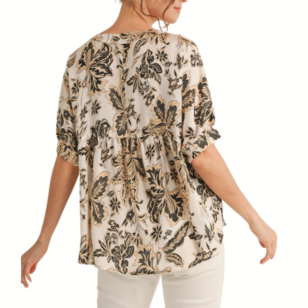 A woman is seen from the back wearing the Fashiongo Flower Print Short Dolman Sleeves Top in beige and black with light pants.