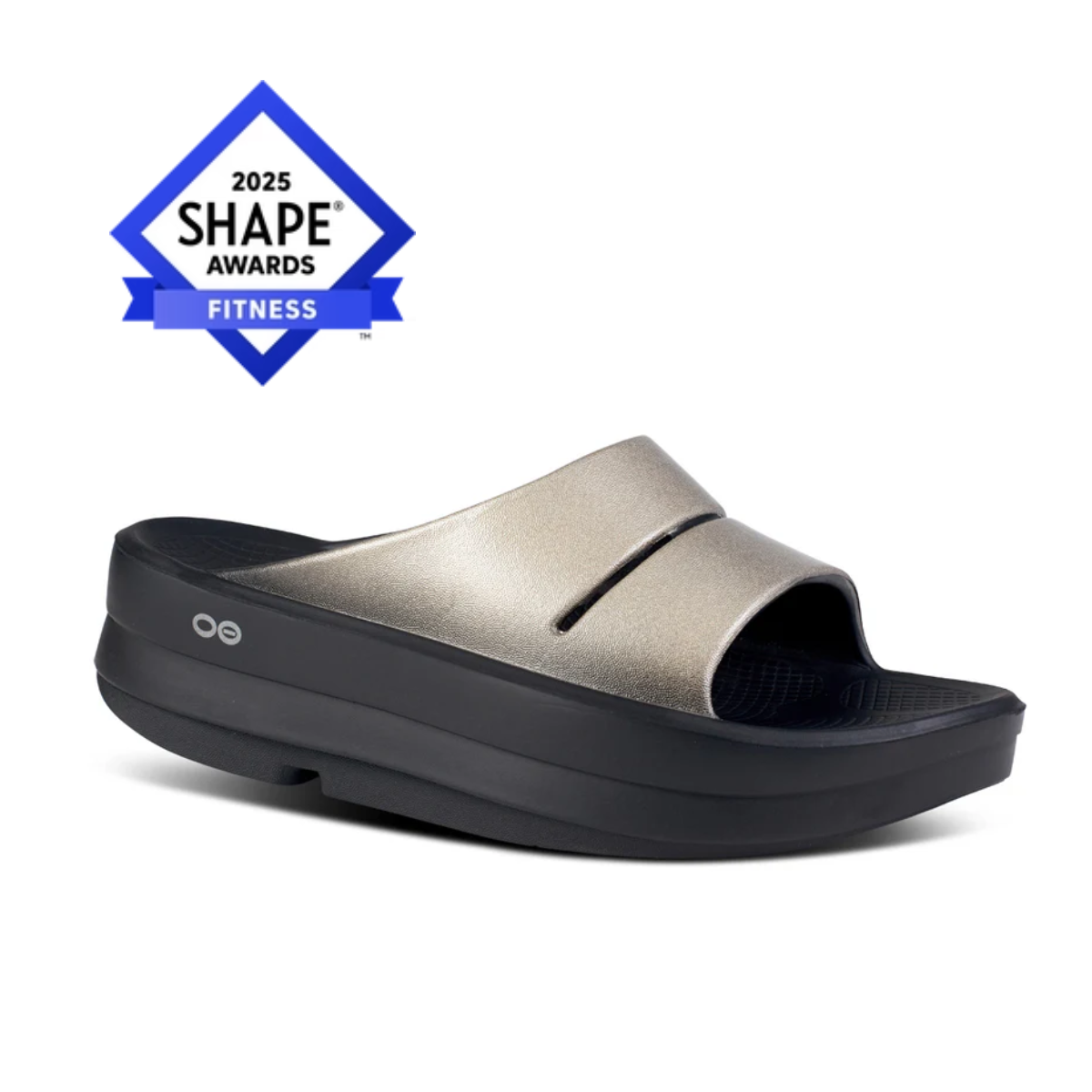 The OOmega Ooahh Luxe Slide in Latte by OOFOS features a metallic design with a thick black sole and an OOmega 2025 Shape Awards Fitness badge on the upper left. Made with OOfoam™ technology, it provides unparalleled comfort for active recovery.