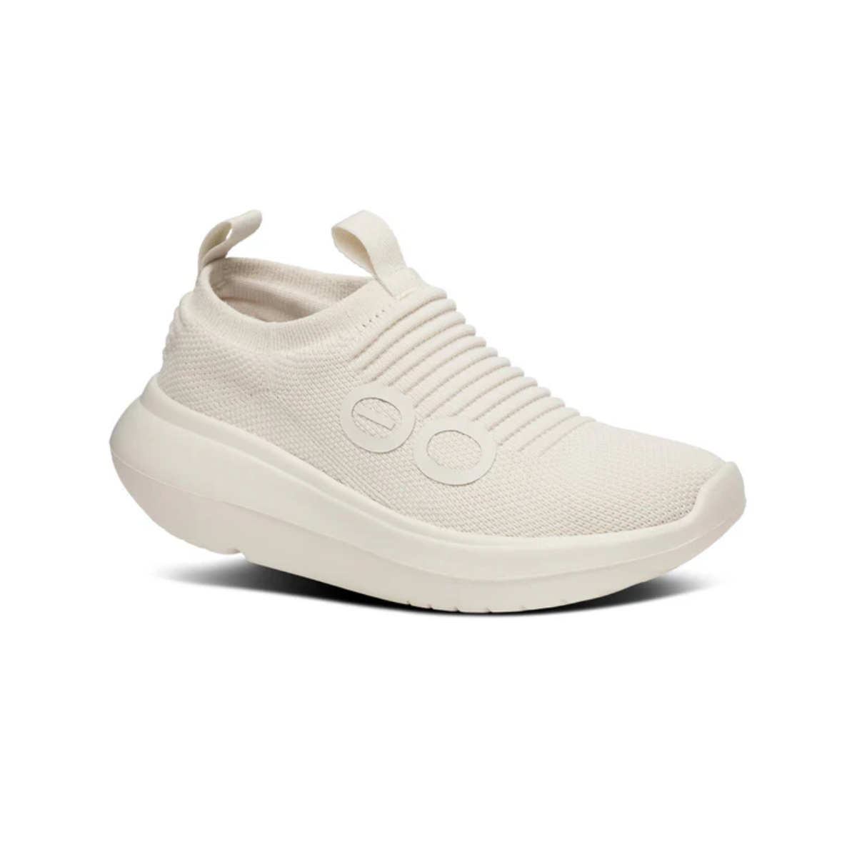 The OO My Zen in Chalk by OOFOS LLC is a beige slip-on sneaker with a knitted, ribbed texture, two oval decorations, and a pull tab. It has a chunky sole with OOfoam technology for enhanced comfort and is designed as an active recovery shoe.
