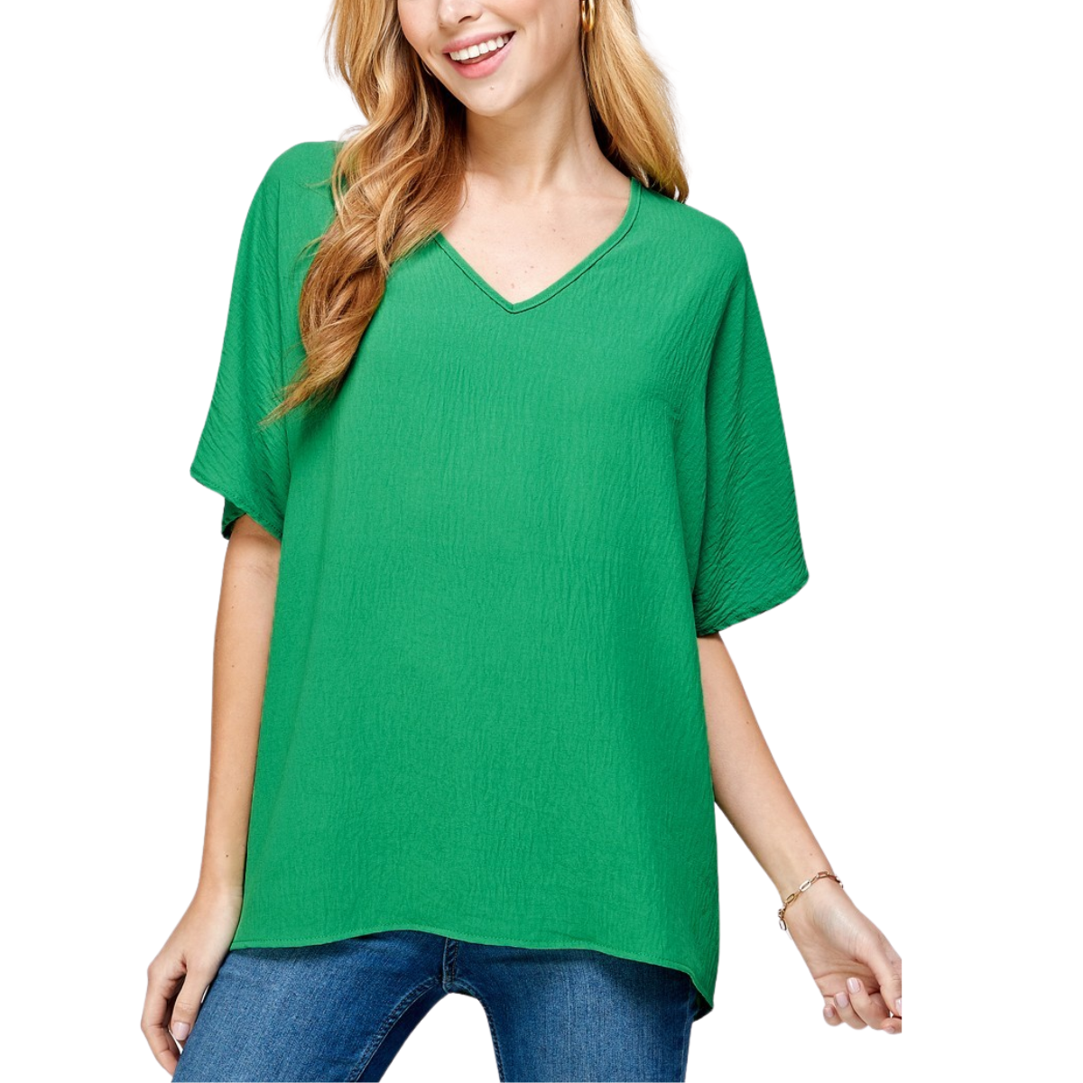 A woman wears the FASHION GO Solid V Neck Oversize Blouse in Green with blue jeans, standing against a white background.