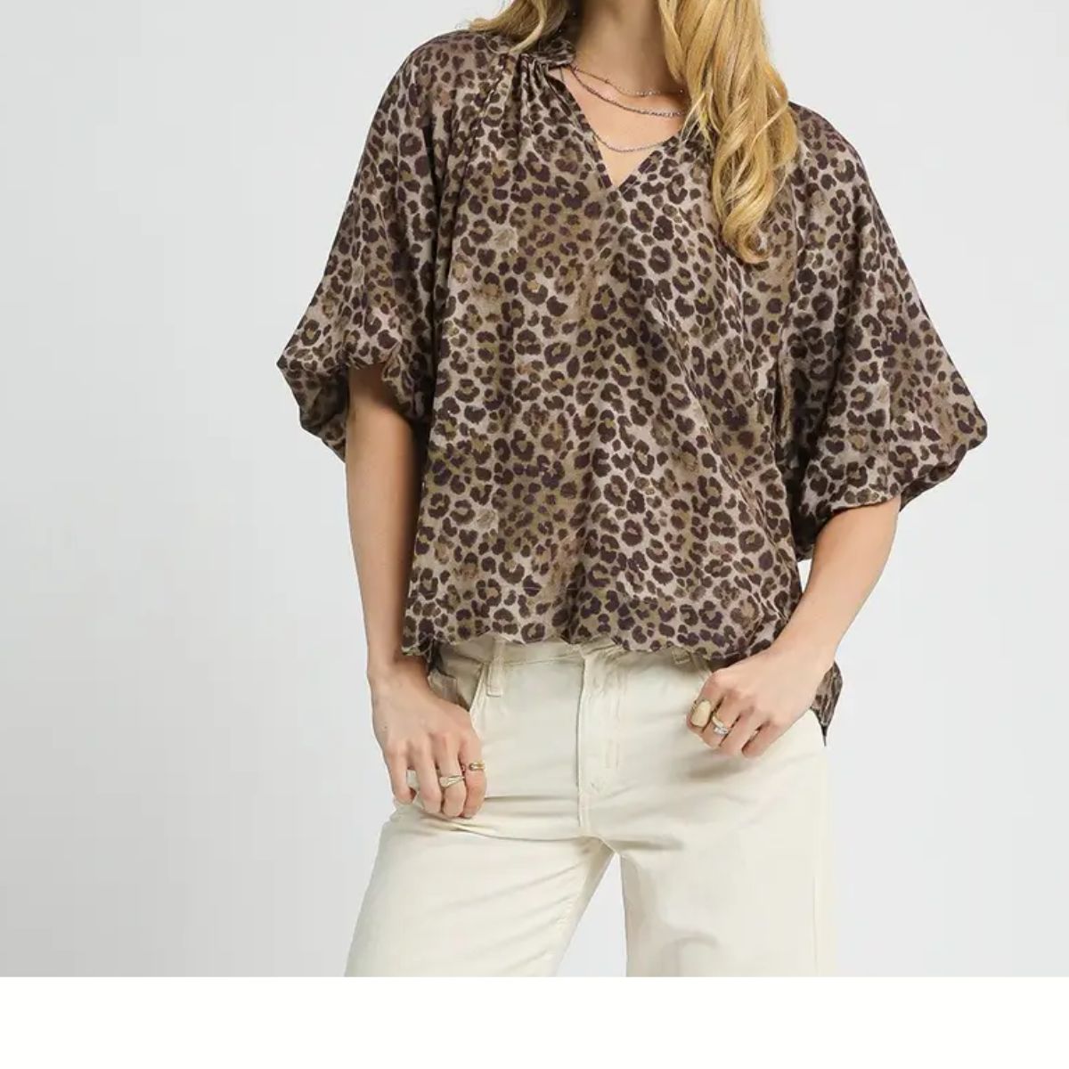 A person styles the Umgee Bubble Sleeve Leopard Print Top with light-colored pants and gold jewelry—a chic choice for any fall wardrobe.