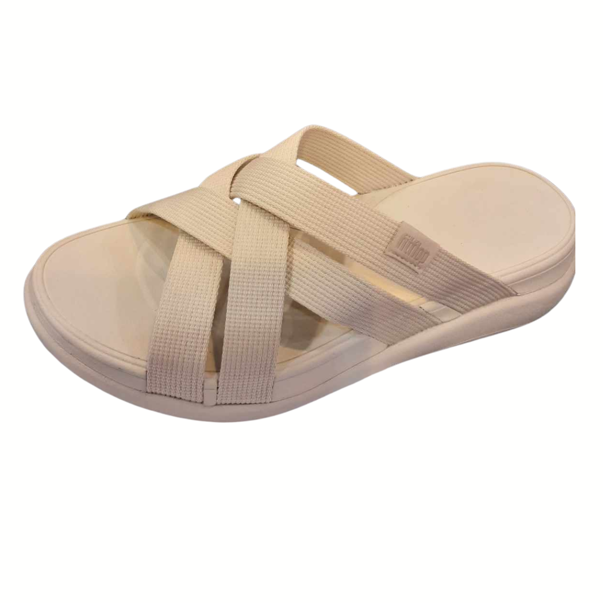 A slightly elevated view of F-Mode Go Webbing Strappy Slides by FIT Flops showcases beige crossed fabric straps, ergonomic design, and a cushioned sole.