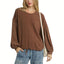 A woman wears the Umgee Linen Long Sleeve Top with Drawstring, paired with light blue jeans and a beige shoulder bag.