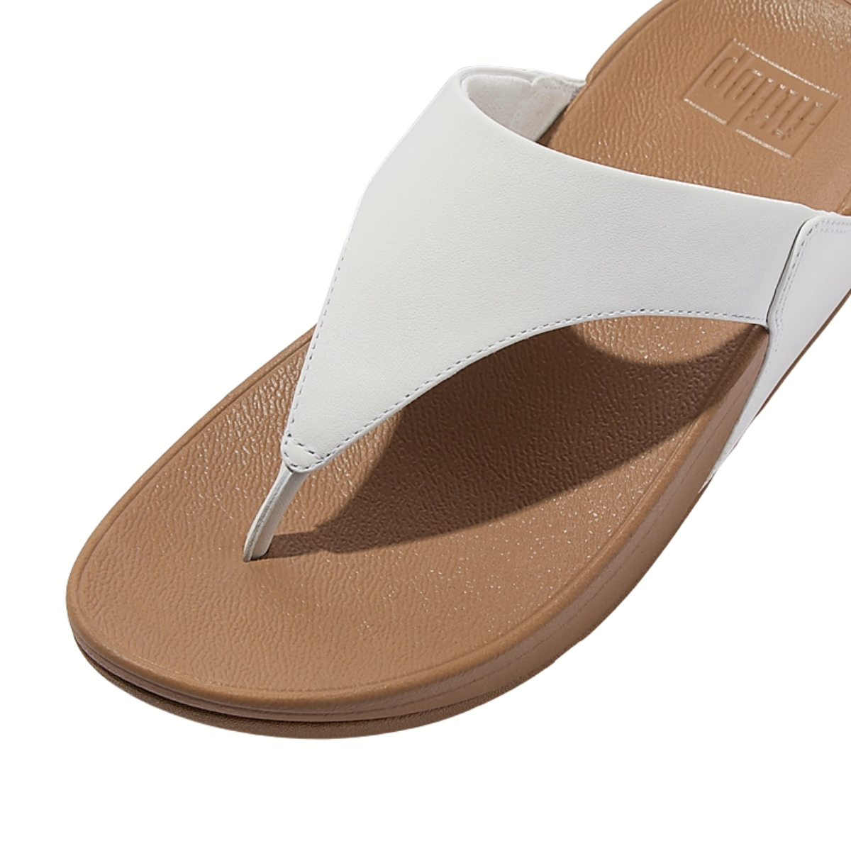 The Fit Flops Lulu Leather Toe Post Thong Flip Flops in White by FITFLOP USA LLC feature ergonomic Microwobbleboard midsoles, a tan textured footbed, and a slightly elevated sole—shown from an angled top view.
