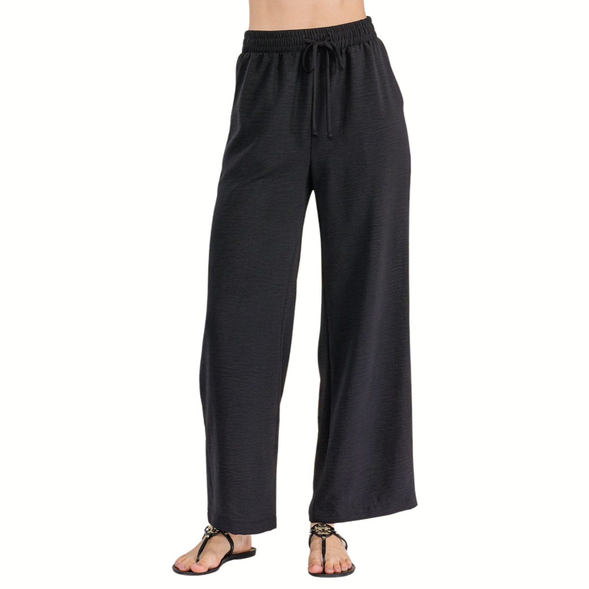 Model wearing FASHION GO Air Flow Fabric Drawstring Pants with Side Pockets in Black and black sandals, standing against a plain white background. Upper body is not visible.