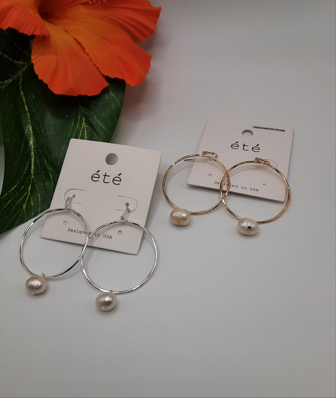 Two pairs of Wire Circle Earrings with Pearl Drop are displayed on SPECIAL EFFECTS branded cards. One pair is silver and the other is gold, set against a backdrop with an orange flower and green leaves.