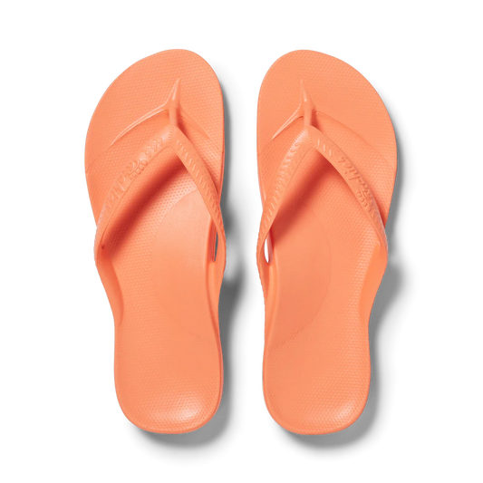 A pair of ARCHIES FOOTWEAR LLC Archies flip flops in Peach arranged neatly against a black background.