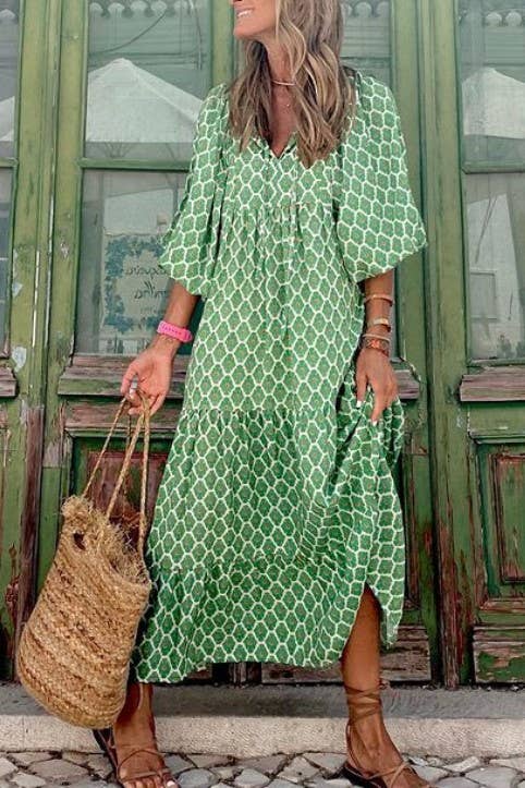 A woman in a Rosa Clothing Bohemian Floral Balloon Sleeves loose flare swing dress holds a woven straw bag, standing before rustic green wooden doors—an ideal look for a beach resort escape.