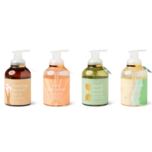 Four colorful bottles of DM MERCHANDISING INC scented Foaming Hand Soap with pump dispensers, each featuring a unique label design.