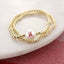 Seasons Jewelry's Alabama Gold & Pearl Logo Stretch Bracelet Set features gold beading and a white pearl with a red "A" Bama logo, elegantly displayed on a white marble surface—a stylish University of Alabama accessory perfect for any fan.