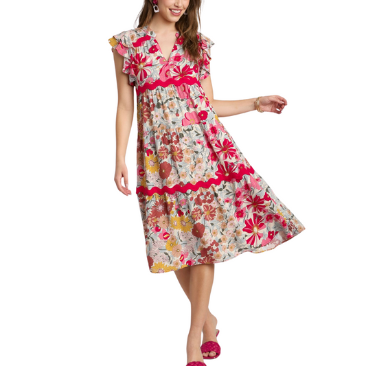 A woman in a FASHION GO Floral Print Split Neck Midi Dress with ruffled sleeves and hem, posing with one hand on her hip.